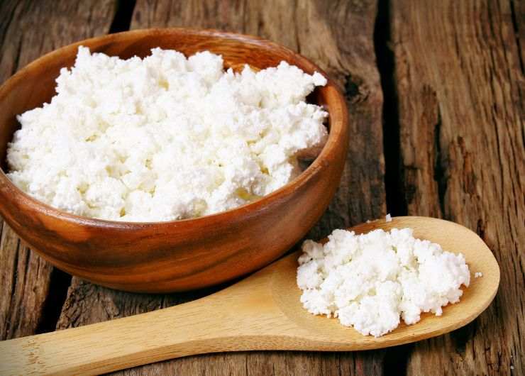 fiocchi di latte in una ciotola di legno e cucchiaio di legno