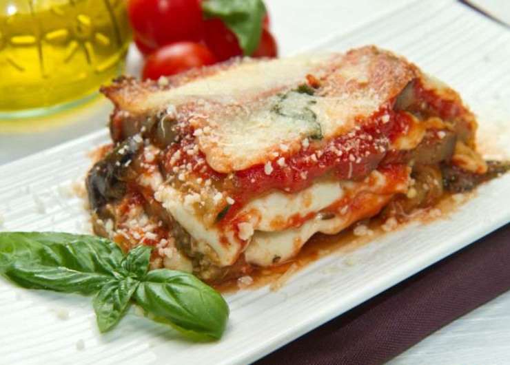 fetta di parmigiana di melanzane con foglie di basilico