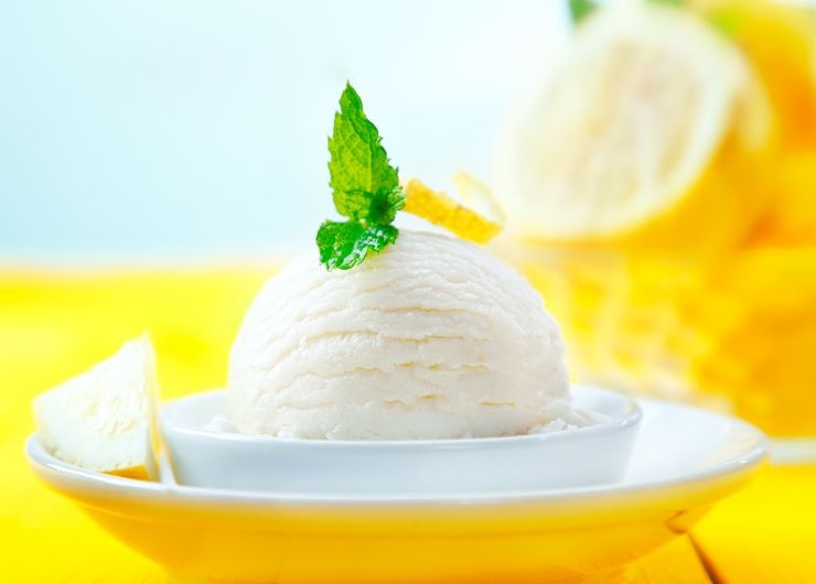 sorbetto al limone in un piattino bianco, menta e limoni