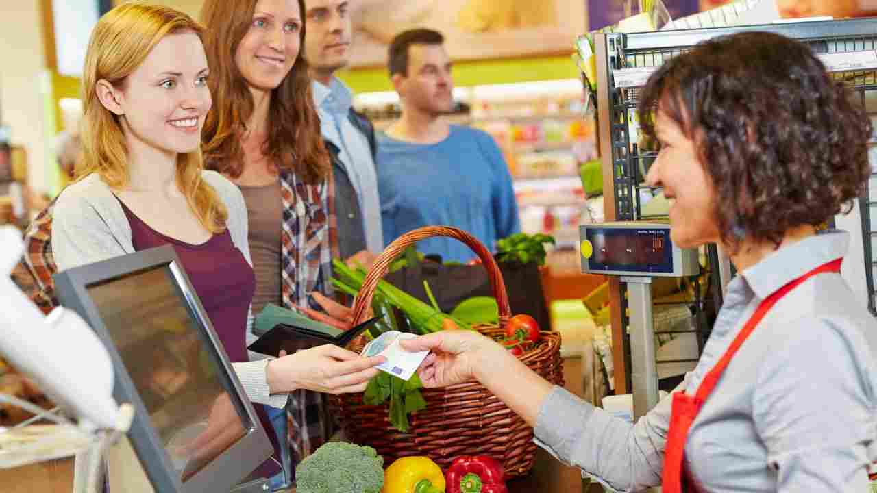 donna paga spesa alla cassa di un supermercato